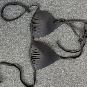 Svart trekantsbikini med snörning - Snygg svart trekantsbikini med knyt i nacken och ryggen. Klassisk modell med lätt vadderade kupor och släta kanter. Märke är Bikbok men har lappen bortklippt. Strl small men skulle passa en medium med mindre byst.