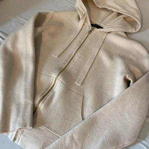 Beige hoodie med dragkedja  - Snygg beige hoodie från Mohito med dragkedja framtill och huva med breda snören. Väldigt liknande soft goat 