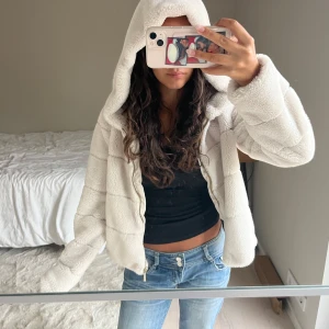 Beige jacka med huva från ONLY - Säljer en fluffig och mysig beige/cremevit teddyjacka från ONLY i storlek XS. Jackan har huva, dragkedja framtill och två fickor på sidorna. Perfekt för dig som gillar en chill och trendig look.🤍