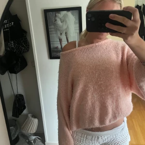 Ljusrosa stickad croppad tröja - Supermysig ljusrosa stickad tröja med croppad passform och bred halsringning som kan bäras offshoulder. Tröjan har långa, lite pösiga ärmar och är perfekt för dig som gillar en chill och trendig stil.