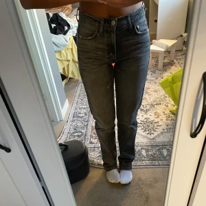 Gråa raka jeans med hög midja - Säljer ett par gråa jeans med hög midja och raka ben. Jeansen har klassisk femficksdesign och stängs med knapp och dragkedja. Snygg tvätt och passar perfekt till en avslappnad stil.