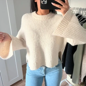 Beige stickad tröja med vida ärmar - Beige stickad tröja med visa ärmar från GinaTricot. Har slits om ärmarna och vid midjan. Väldigt fin på. Använd ett fåtal gånger, kommer i mycket bra skick. 