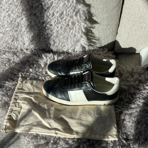 Valentino flycrew  - Svartvita sneakers från Valentino Garavani med klassisk svart färg. Skorna är i skinn och har ikoniska nitar baktill på sulan samt kamouflagemönstrad undersida. Perfekt för dig som gillar lyxiga och stilrena sneakers. Dom är i superbra skick och alla biter sitter kvar, hör av dig om funderingar😇
