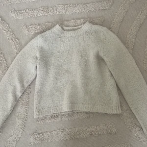 Ljus stickad tröja från Vero Moda - Mysig ljusbeige stickad tröja från Vero Moda i storlek S. Tröjan har en rund halsringning, långärmade ärmar och en lite croppad passform. 