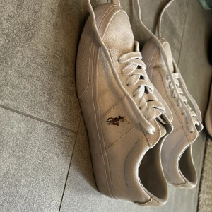 Vita sneakers från Polo Ralph Lauren - Snygga vita sneakers från Polo Ralph Lauren med klassisk snörning och rund tå. Skorna har canvasmaterial med mockadetalj på hälen och Polo-logga på sidan och bak. Perfekt för dig som gillar stilrena skor med detaljer . Utgångspriset var 1200kr, men säljer för 800kr. Pris kak förhandlas! Jag tvättar skosnören innan försäljning. Så det är i bästa skick . Dessa går även att tvätta i maskin 