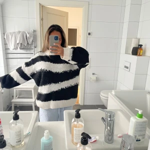 Svartvit randig stickad tröja - Mjuk och oversized stickad tröja med breda svarta och vita ränder. Tröjan har lång ärm och ribbad kant vid hals, ärmslut och nederkant. Perfekt för dig som gillar chill och comfy stil med lite extra attityd.