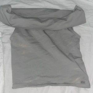 Grå axelbandslös tubtopp  - Snygg grå tubtopp från pull and bear med bred, vikt kant upptill. Perfekt för dig som vill ha en enkel topp att matcha med allt. Mjuk och stretchig, sitter skönt och är lätt att bära till både jeans och kjol.