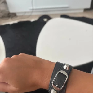 Balenciaga grått läderarmband - Snyggt grått armband från Balenciaga i läder med coola silverfärgade metalldetaljer och spänne. 
