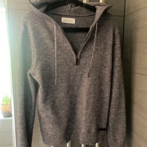 Grå stickad hoodie från Pier One - Mysig grå stickad hoodie från Pier One med dragkedja framtill och huva med snören. Perfekt för kyliga dagar och enkel att matcha med olika outfits. Ribbstickade muddar vid ärmslut och nederkant. Liknar merinoull, hör av er vid minsta fundering!!!