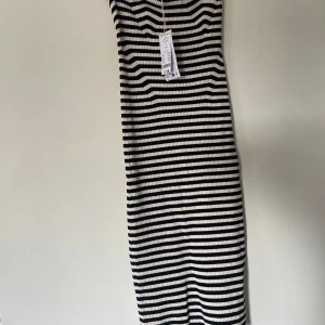Randig tubklänning svart/vit L - Säljer en ribbad tubklänning med svarta och vita horisontella ränder. Klänningen är stickad och har en kroppsnära passform som framhäver siluetten. Perfekt för dig som gillar enkel och stilren design med lite edge.