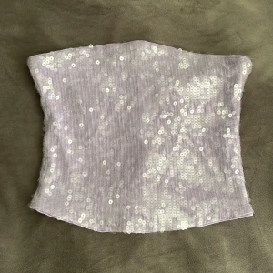 Ljuslila paljett-tubtopp Gina Tricot - Superfin ljuslila tubtopp från Gina Tricot, täckt med glittriga paljetter. Köpte den förra månaden men kommer ej till användning 🤗. Toppen har dragkedja bak för enkel påklädning och sitter snyggt croppad. Pris kan diskuteras!!