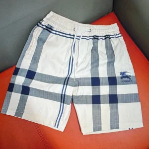 Rutiga shorts med snörning - Snygga shorts i klassiskt rutigt mönster med vita och blå toner. De har elastisk midja med snörning. Perfekt för dig som vill ha en clean och lyxig vibe i sommar. Materialet känns lätt och skönt mot huden.