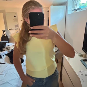 Gul ärmlös topp med volangaxlar från vcode  - Superfin stickad topp från vcode Paris, storlek onesize 