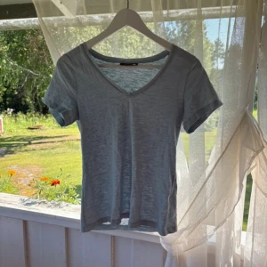 Ljusblå v-ringad t-shirt KappAhl XS - En basic ljusblå t-shirt från KappAhl i storlek XS. T-shirten har v-ringning, korta ärmar och är gjord i ett tunt och mjukt bomullstyg. Perfekt till jeans eller shorts för en chill look.