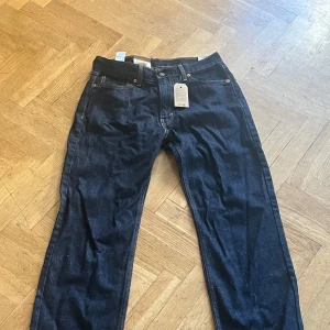 Levi's 555 mörkblå jeans W30 L32 - Mörkblå Levi's 555 jeans med relaxed fit och raka ben. Klassisk femficksmodell med snygga kontrastsömmar och ikonisk läderpatch bak. Tillverkade i slitstarkt denimtyg av bomull. 