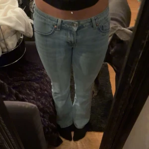 Ljusblå bootcut jeans  - Säljer ett par ljusblå jeans  med bootcut passform och klassisk femficksdesign. Jeansen har låg midja och är tillverkade i mjukt denimtyg som sitter snyggt över höfterna och släpper ut vid bensluten. Perfekta för en chill och trendig look.