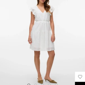 Vit spetsklänning med volangärmar - Superfin vit kortklänning i bomull med spetsdetaljer och volangärmar. Klänningen har v-ringning, markerad midja och ärmlös design med romantiska volanger. Bara använd 1 gång. Originalpris: 499kr. Storlek xs men passar även s