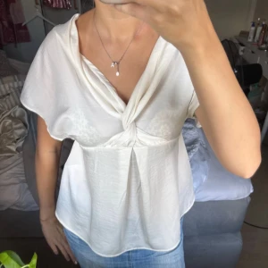 Vit omlott blus från InWear - Säljer en vit blus från InWear med snygg omlott-detalj framtill och lös passform. Blusen har korta ärmar och ett mjukt, lätt material som känns skönt mot huden. Perfekt att styla med jeans eller kjol för en fräsch look.