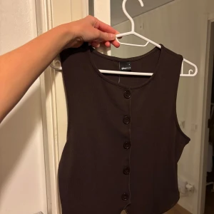 Brun väst med knappar från Gina Tricot - Snygg brun väst från Gina Tricot som fortfarande har prislappen kvar. Säljs pga att jag redan har en liknade. 