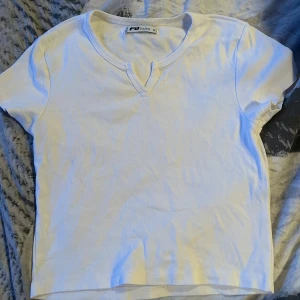 Vit t-shirt från FB Sister - Säljer en enkel och stilren vit t-shirt från FB Sister/ New Yorker. Den har en v-ringad hals och korta ärmar. Den är i nyskick. Skicka ett meddelande vid intresse!