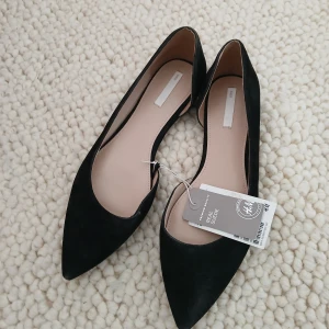 Nya mocka ballerinaskor , strl 40, från H&M Premium - Snygga svarta ballerinaskor i äkta mocka från H&M. De har en elegant spetsig tå och är perfekta för en stilren look. Skorna är märkta med 'Premium Quality' och har en bekväm passform.