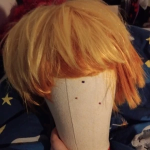 Zenitsu peruk - Demon slayer - Snygg peruk i en mix av blonda och orange toner. Perfekt för cosplay eller maskerad. Den har en rufsig stil med korta längder som ger en cool look. Aldrig använd.