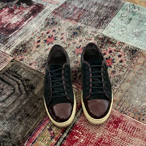 Svarta sneakers från Lanvin - Snygga svarta sneakers från Lanvin med vinröda detaljer. Skorna har en klassisk snörning och en vit sula som ger en stilren look. Perfekta för en trendig vardagsstil. I väldigt bra skick som syns på bilderna, 8/10. Framsidorna är i princip som nya utan nästan några repor. Storlek 45, innermått 29,5 cm. Pris 1799 men kan diskuteras något vid snabb och smidig affär! Hör av dig!