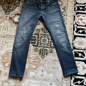 Jacob Cohen - Snygga blå jeans från Jacob Cohen med slitna detaljer och gul brodering vid fickan. Tillverkade av japanskt utvalt tyg med italienskt hantverk. Perfekta för en avslappnad stil. Väldigt bra skick 8/10 och skönt material. Storlek 36 men sitter som 33/34. Passar dig som är runt 188. Tveka inte på att höra av dig!