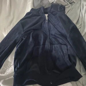 Mörkblå tröja från juicy couture  - Säljer en snygg mörkblå zipp tröja från Juicy Couture. Den har en dragkedja framtill och en praktisk känguruficka. Perfekt för en avslappnad stil.💙