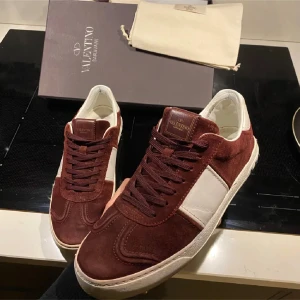 Ett par vinröda flycrews från Valentino. - Snygga sneakers från Valentino i en kombination av mocka och vita detaljer. Skorna har snörning och en klassisk design som passar perfekt för en stilren look. 2 nitar på vardera sko är av, men annars jättefint skick, boxen på bilden ingår tyvär inte, hör av er vid frågor och funderingar!😄