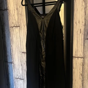 Svart klänning från Zay Clothing - Elegant svart klänning från Zay Clothing med paljettdetaljer och v-ringad design. Klänningen har breda axelband och en smickrande passform som passar perfekt för festliga tillfällen.