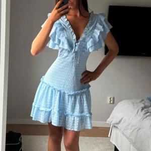 Ljusblå klänning med volanger - S