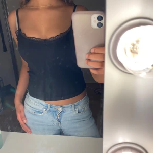 Svart linne med spets - Snyggt svart linne med spetsdetaljer längs urringningen. Perfekt för en stilren look. Linnet har smala axelband och en figurnära passform. Väldigt bekvämt linne! 