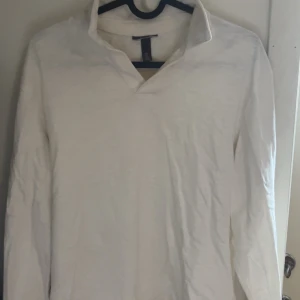 Vit långärmad pikétröja - Säljer en stilren vit långärmad pikétröja med krage. Perfekt för en avslappnad men ändå uppklädd look. Passar bra till både jeans och chinos. Pris går att diskutera vid snabb och smidig affär!