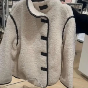 Vit teddyjacka med svarta detaljer - Säljer denna. Vill annars gärna byta denna som är i storlek M till en S så om någon har i S och vill byta med denna så hör gärna av er. 