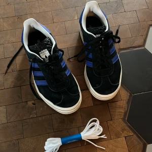 Adidas Gazelle Bold i svart och blå🩵 - Skit snygga Adidas Gazelle sneakers i svart mocka med blå detaljer och vita sulor. Storlek 36 2/3 är tyvärr lite små för mig. Vita snören ingår.🩵🩵Kan gå ner i pris. 