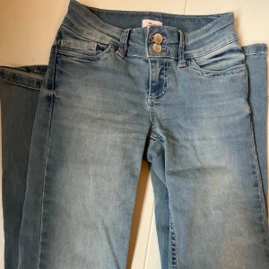 Blå bootcut jeans med broderade fickor - Snygga blå bootcut jeans med relativt låg midja och unika röda broderier på bakfickorna. 