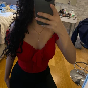 Röd offshoulder topp från NLY - Säljer en snygg röd offshoulder topp från Nelly. Toppen har en söt knytning framtill och volangdetaljer vid ärmarna. Perfekt till sommaren .