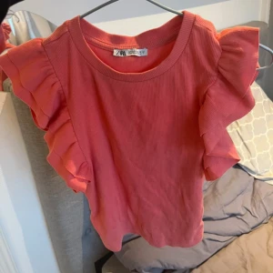  volangtopp från Zara - Säljer en söt rosa/apricos topp från Zara med volangdetaljer på ärmarna. Toppen har en rund halsringning. Mycket sparsamt använd. Storlek S🧡