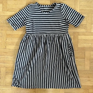 Randig klänning från Gudrun Sjödén - Säljer en randig klänning från Gudrun Sjödén i svart och beige. Klänningen har korta ärmar och en rund halsringning. Perfekt för en avslappnad stil. Tillverkad i Grekland. Finns hund och katt i hemmet.