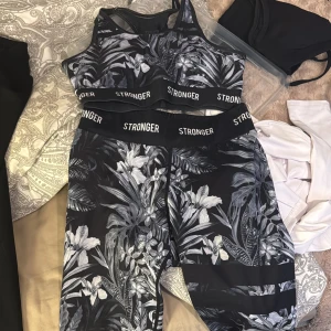 Svart och vit blommig sporttopp från Stronger - Säljer ett set från stronger, en träningsbh och ett par tights, båda i storlek S
