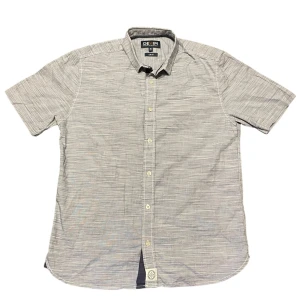 Grå kortärmad skjorta från Hampton Republic - Snygg grå kortärmad skjorta från Hampton Republic i slim fit. Skjortan har ett diskret randigt mönster och knappar framtill. Perfekt för en stilren look.