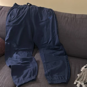 Svarta mjukisbyxor från Gola - Säljer ett par svarta mjukisbyxor från Gola. Byxorna har en elastisk midja med snörning och två sidofickor. Perfekta för en avslappnad stil.