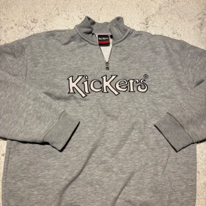 Grå tröja med zip från Kickers - Säljer en grå tröja från Kickers med zip och broderad logga på bröstet. Skit snygg till som gillar relaxed fit och bekväma tröjor att ha över. S men passar jättebra för M också