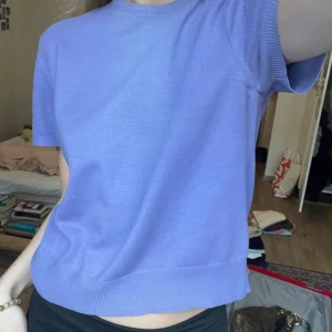 Ljuslila kortärmad topp - Säljer en ljuslila topp med korta ärmar. Toppen har en enkel och stilren design med ribbade kanter vid ärmslut och nederkant. Perfekt för en avslappnad look.