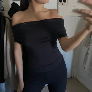 Svart offshoulder topp - Säljer en stilren svart offshoulder topp som sitter tight och framhäver figuren. Perfekt för en kväll ute eller en avslappnad dag. Toppen är enkel att matcha med olika outfits.