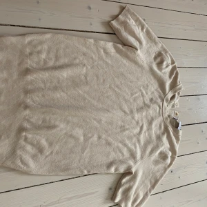 Beige tröja från Zara - Säljer en stilren beige tröja från Zara med korta ärmar och knappar vid nacken. Perfekt för en avslappnad look. Tröjan är tillverkad i ett mjukt material som känns skönt mot huden. Köpt för 329kr men säljer för 250kr