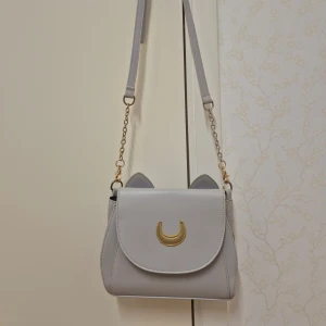 Ljusgrå Sailor Moon axelväska - Använt skick. Lite fläckar och lädret från månen har lossnat lite, se bild.