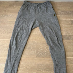Grå mjukisbyxor från Lyle & Scott - Jag säljer nu mina gråa mjukisbyxor från Lyle & Scott med elastisk midja och snörning. Klassisk gul logga på vänster höft. Passar mig bra cirka (185cm lång) 