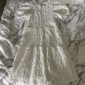 Vit klänning med blom mönster - Superfin vit klänning med broderat tyg, puffärmar och öppen rygg. Trots att det är i barn storlek (152) skulle jag säga att den passar dom som har xxs💞 Säljer den då den inte längre kommer till användning🥰